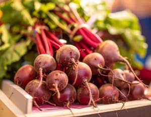 Frische Bünde Rote Bete mit kräftigen grünen Blättern auf einem Marktstand als gesundes, naturbelassenes Gemüse.