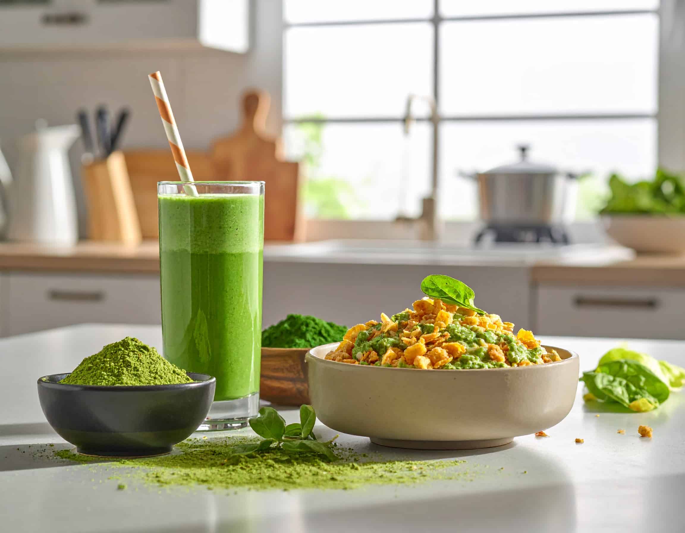 Grüner Gerstengras-Smoothie und eine Frühstücks-Bowl mit Pflanzenpulver als Inspiration für eine nährstoffreiche Ernährung.