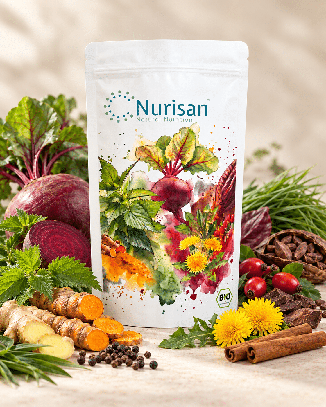 Eine weiße Standbodenbeutel-Verpackung der Marke Nurisan steht im Mittelpunkt, umgeben von frischen Zutaten wie Roter Bete, Kurkuma, Ingwer, Löwenzahn, Zimtstangen und Kräutern vor einem hellen Hintergrund.
